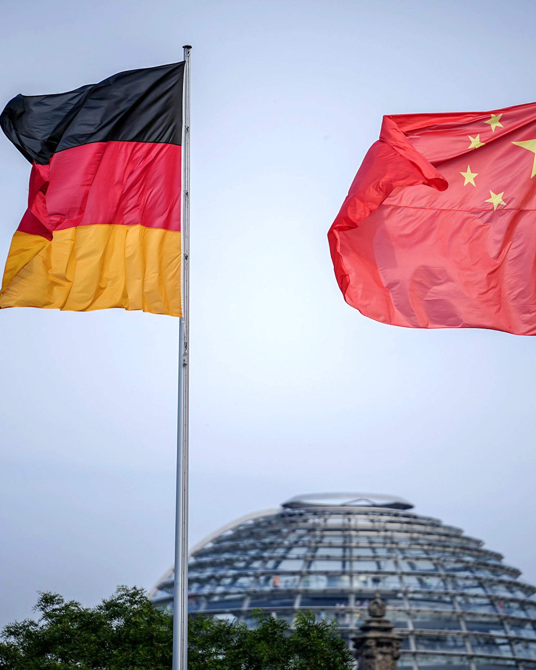 Die Flaggen von Deutschland und China wehen im Juni 2023 zum Auftakt des Deutschland-Besuchs der chinesischen Regierung im Wind vor dem Bundeskanzleramt, im Hintergrund die Kuppel des Reichstagsgebäudes.