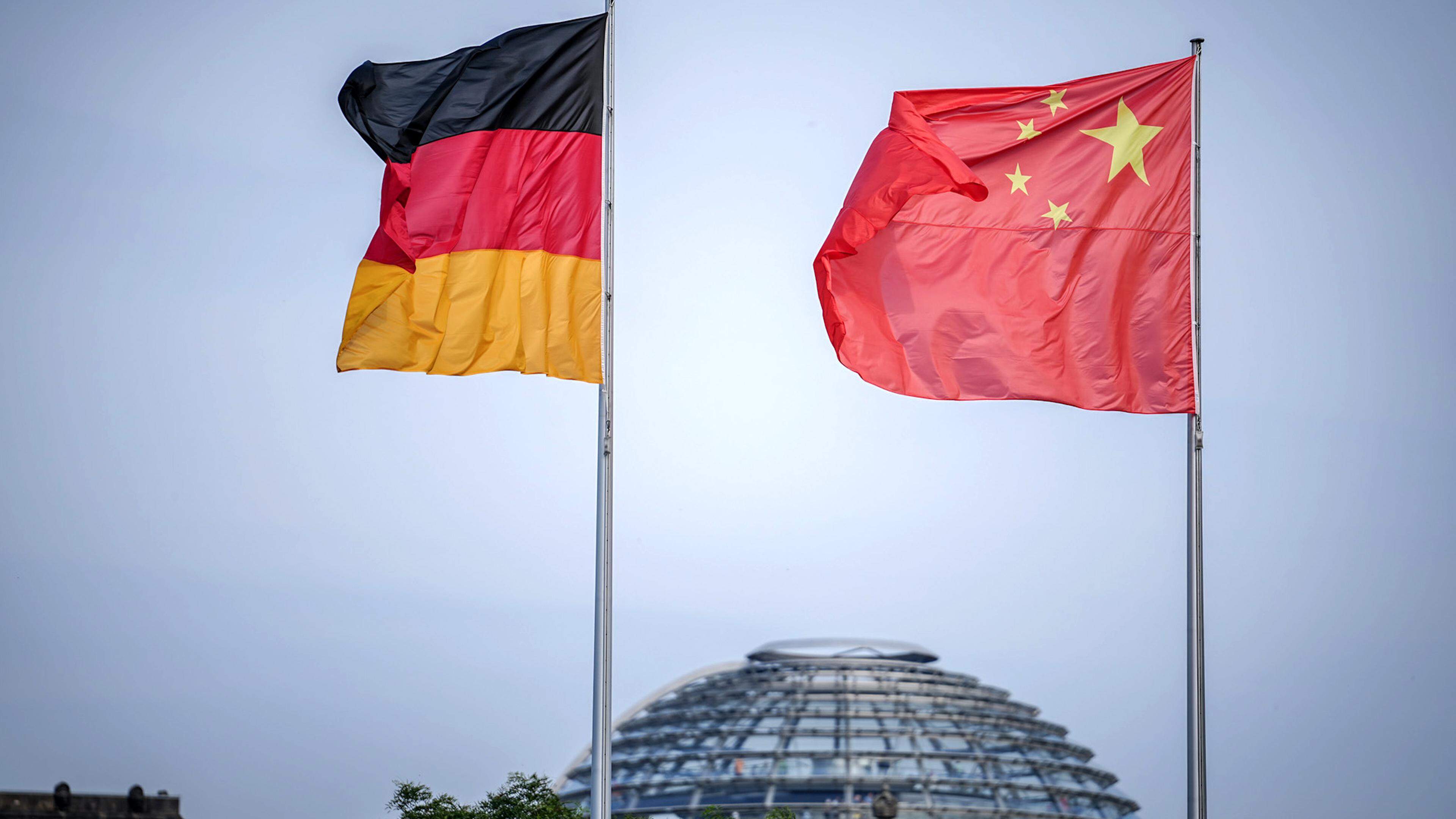 Die Flaggen von Deutschland und China wehen im Juni 2023 zum Auftakt des Deutschland-Besuchs der chinesischen Regierung im Wind vor dem Bundeskanzleramt, im Hintergrund die Kuppel des Reichstagsgebäudes.