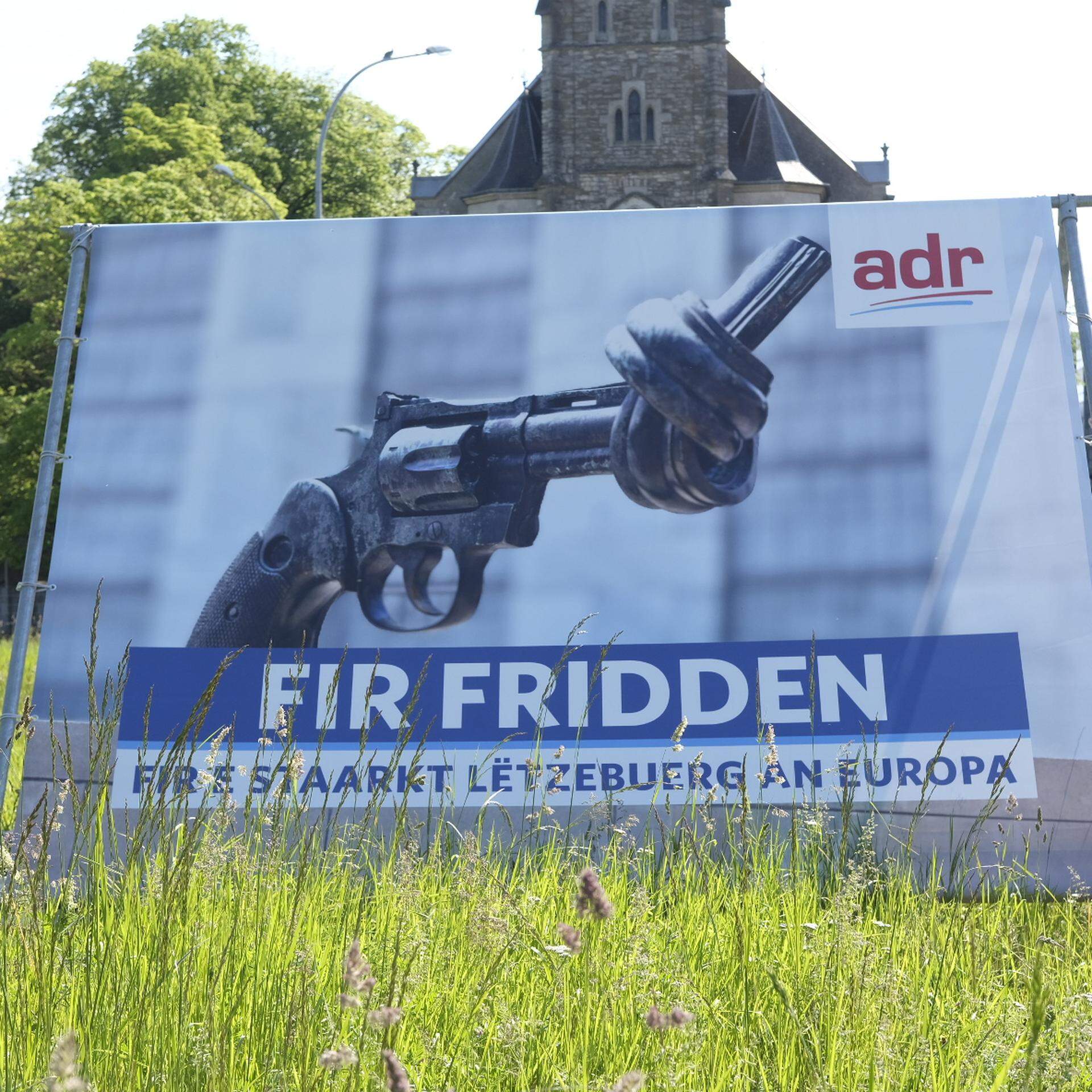 Mit Kunst und Populismus auf Stimmenfang: Das ADR-Wahlplakat vor der Hollericher Kirche. Es handelt sich um ein Foto eines der drei Originalskulpturen von „Non Violence“, jener, die vor dem UN-Hauptsitz in New York steht. 
