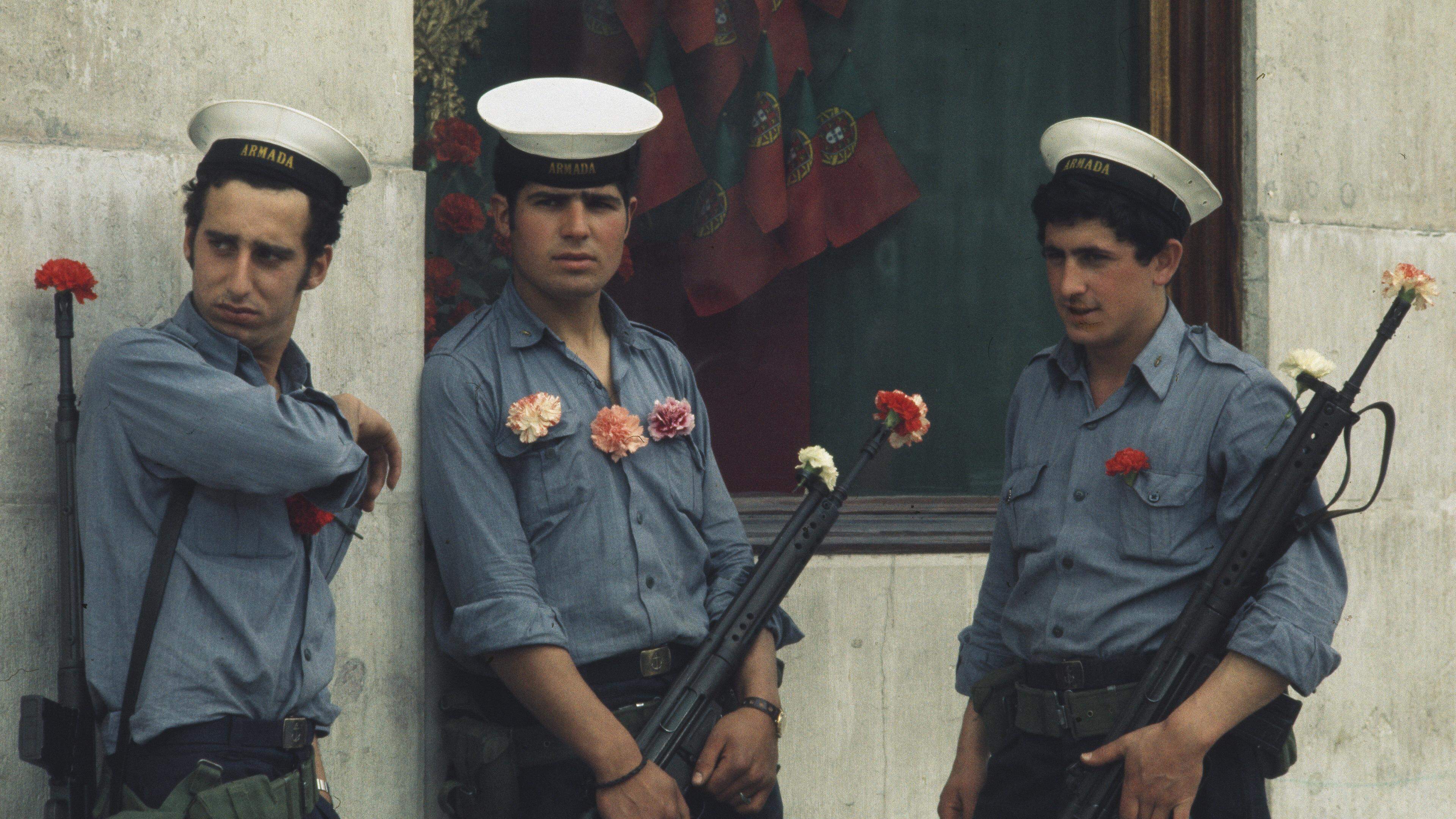 Portuguese soldiers with carnations on their uniforms and in their gun barrels stand guard in Lisbon on April 29th, 1974. The carnation is a symbol of the 'Carnation Revolution' military coup that ended nearly 50 years of dictatorship in Portugal. (Photo by UPI/Bettmann Archive/Getty Images)