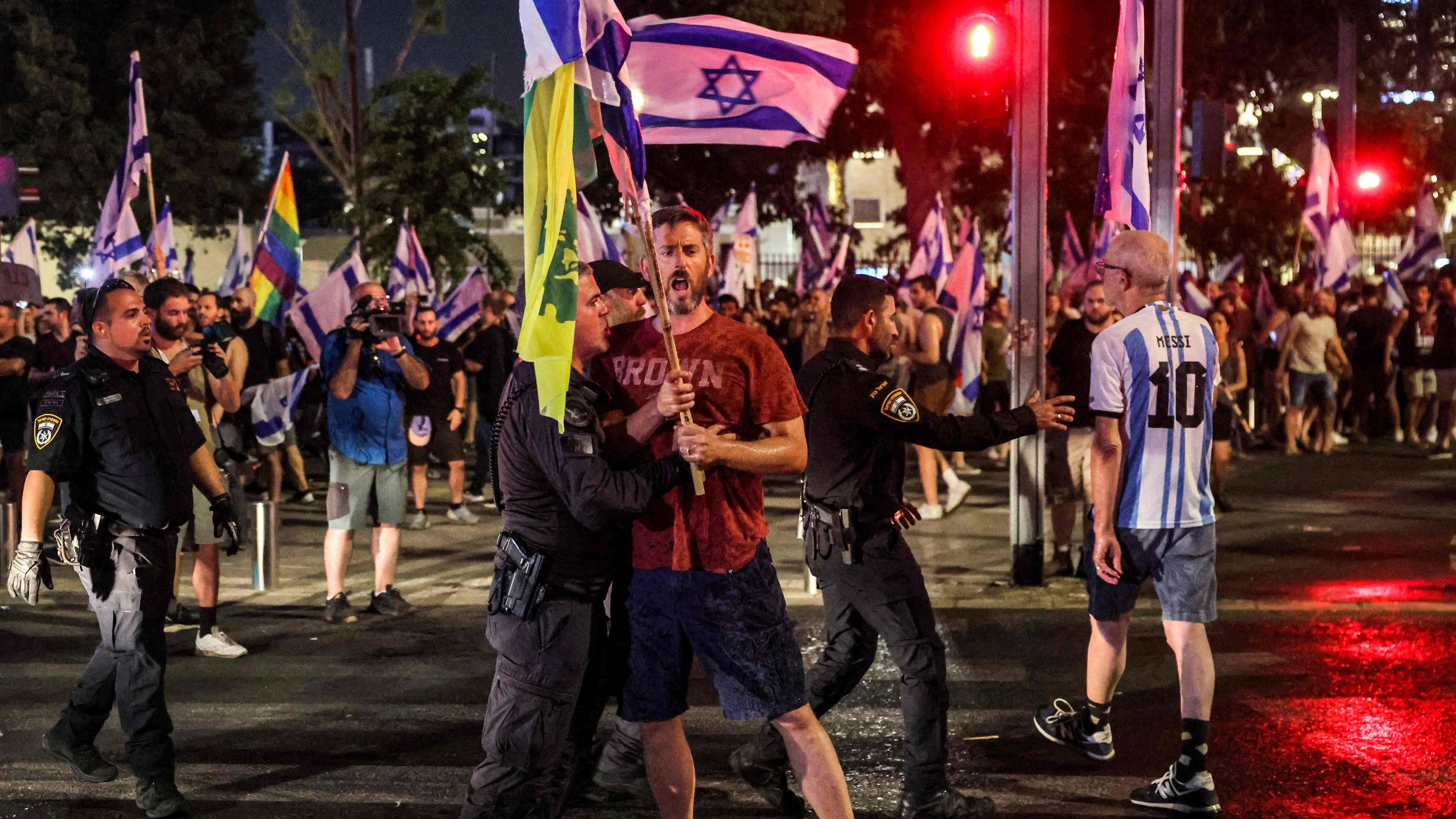 Ein Demonstrant wird während einer Protestkundgebung gegen den Justizreformplan der israelischen Regierung in Tel Aviv von einem israelischen Bereitschaftspolizisten festgehalten.