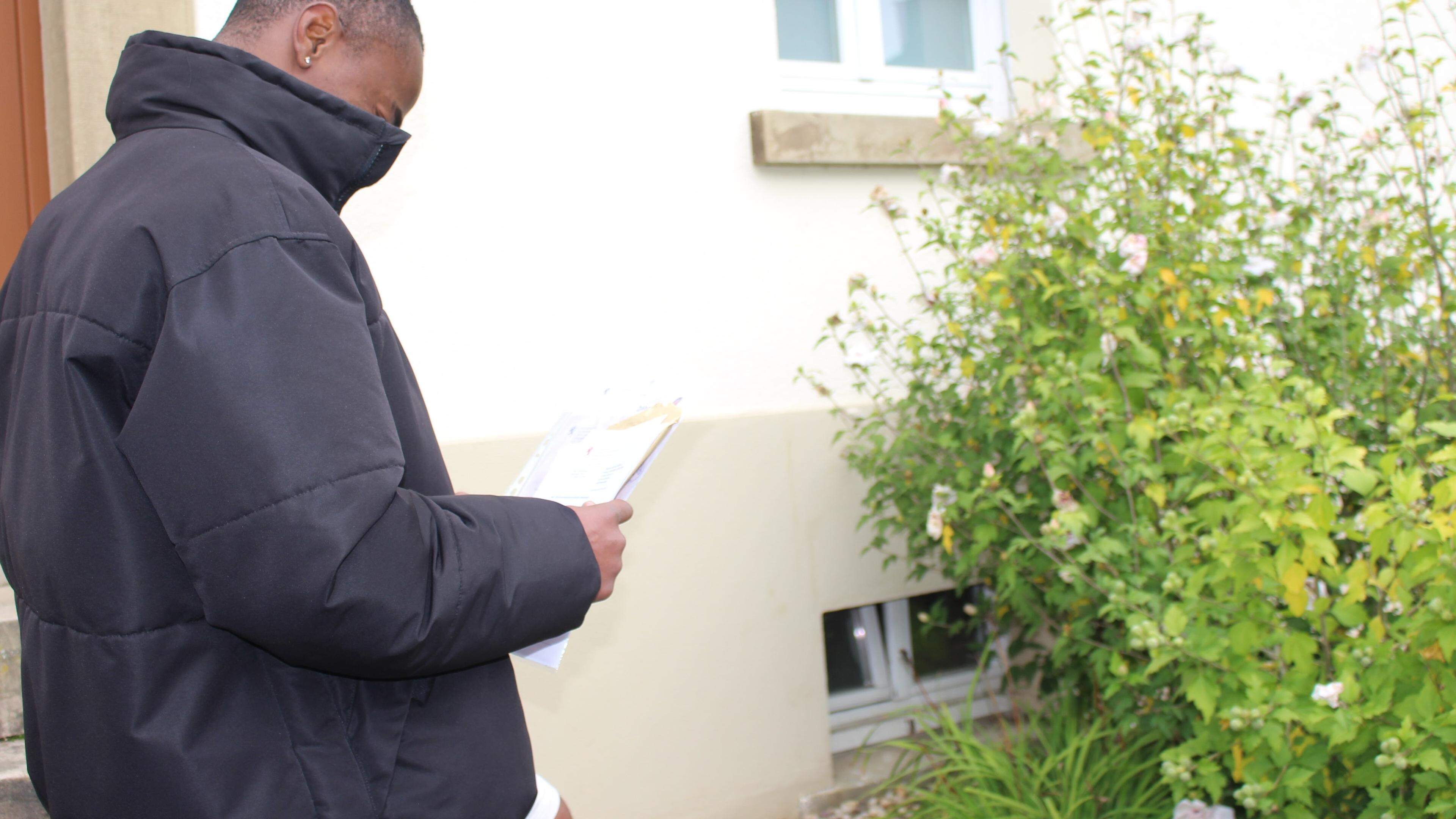 Der junge Mann aus Kamerun hält Bescheide der Behörden in der Hand. Ihr Antrag auf Asyl wurde in Luxemburg abgelehnt.