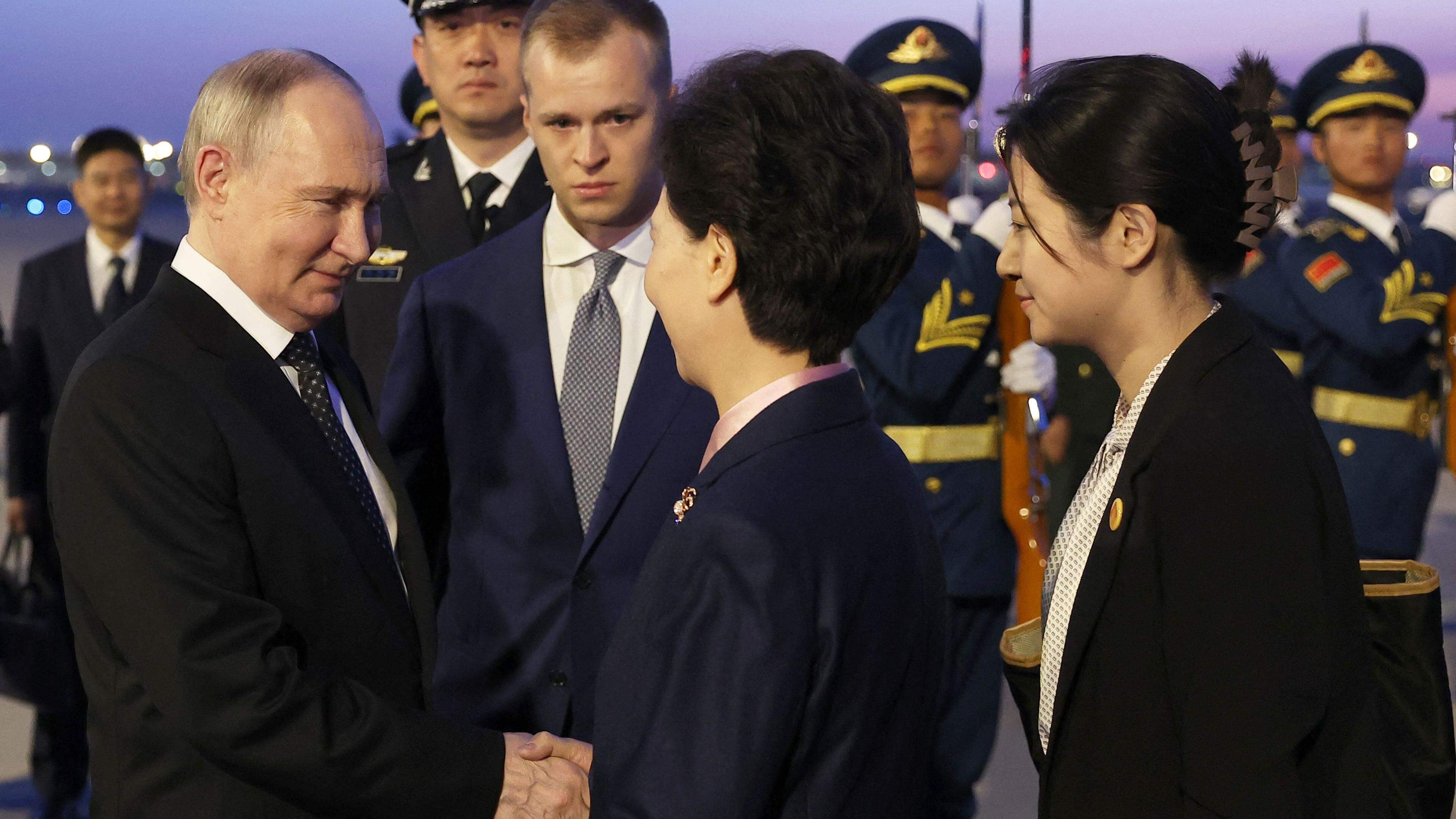 In this pool photograph distributed by the Russian state agency Sputnik, Russia's President Vladimir Putin (L) shakes hands with Chinese State Councilor Shen Yiqin upon his arrival at the Beijing Capital International Airport in Beijing on May 16, 2024. (Photo by Alexander Ryumin / POOL / AFP) / ** Editor's note : this image is distributed by Russian state owned agency Sputnik **