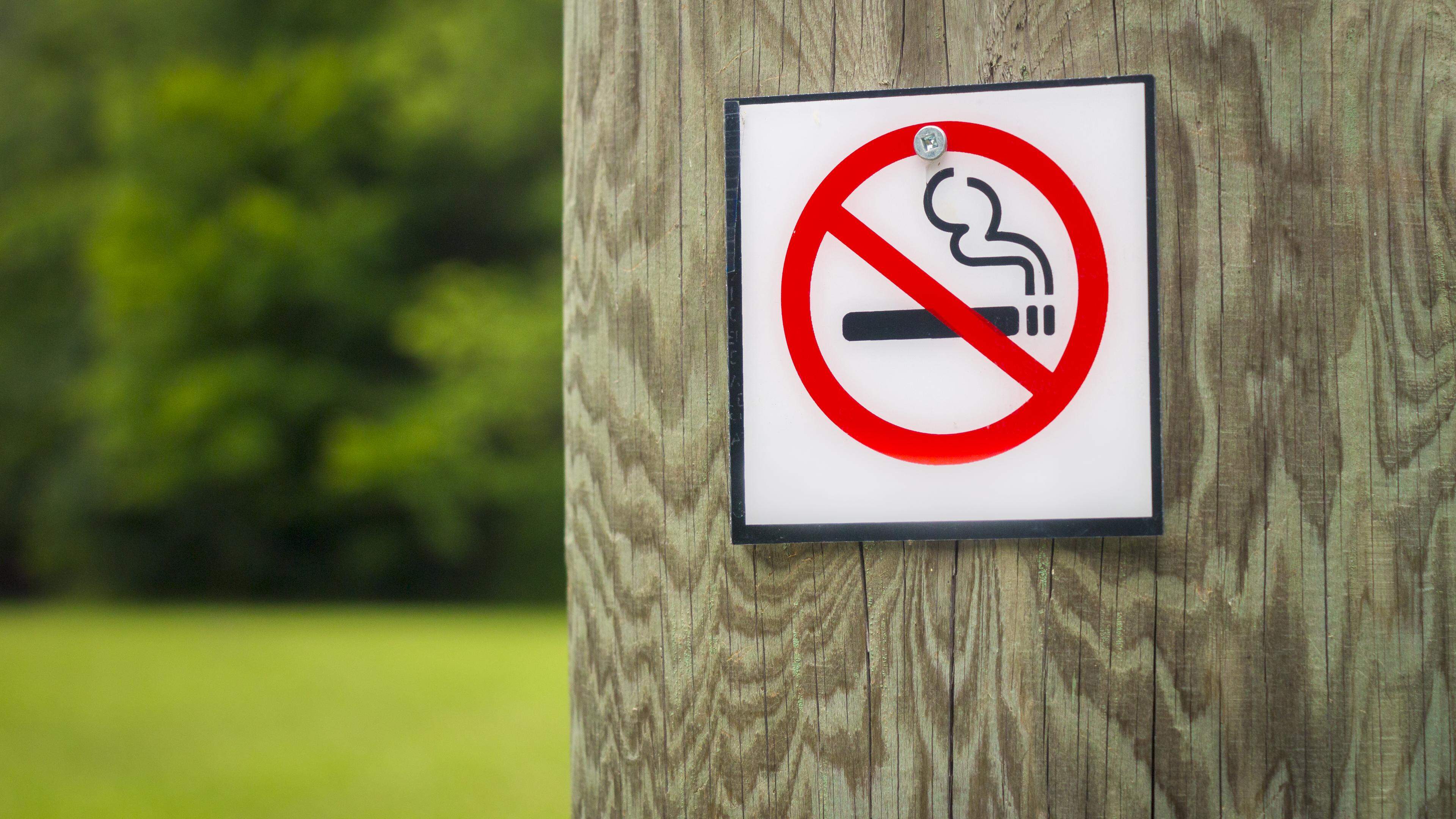 No smoking sign, outside on a wooden post.