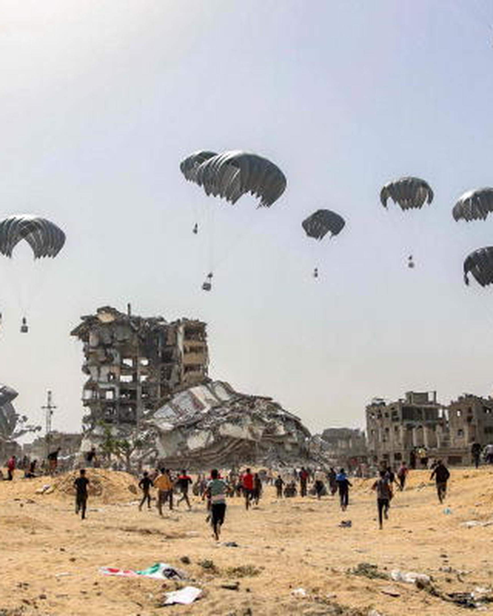 TOPSHOT - People rush to landing humanitarian aid packages dropped over the northern Gaza Strip on April 23, 2024 amid the ongoing conflict in the Palestinian territory between Israel and the militant group Hamas. (Photo by AFP)