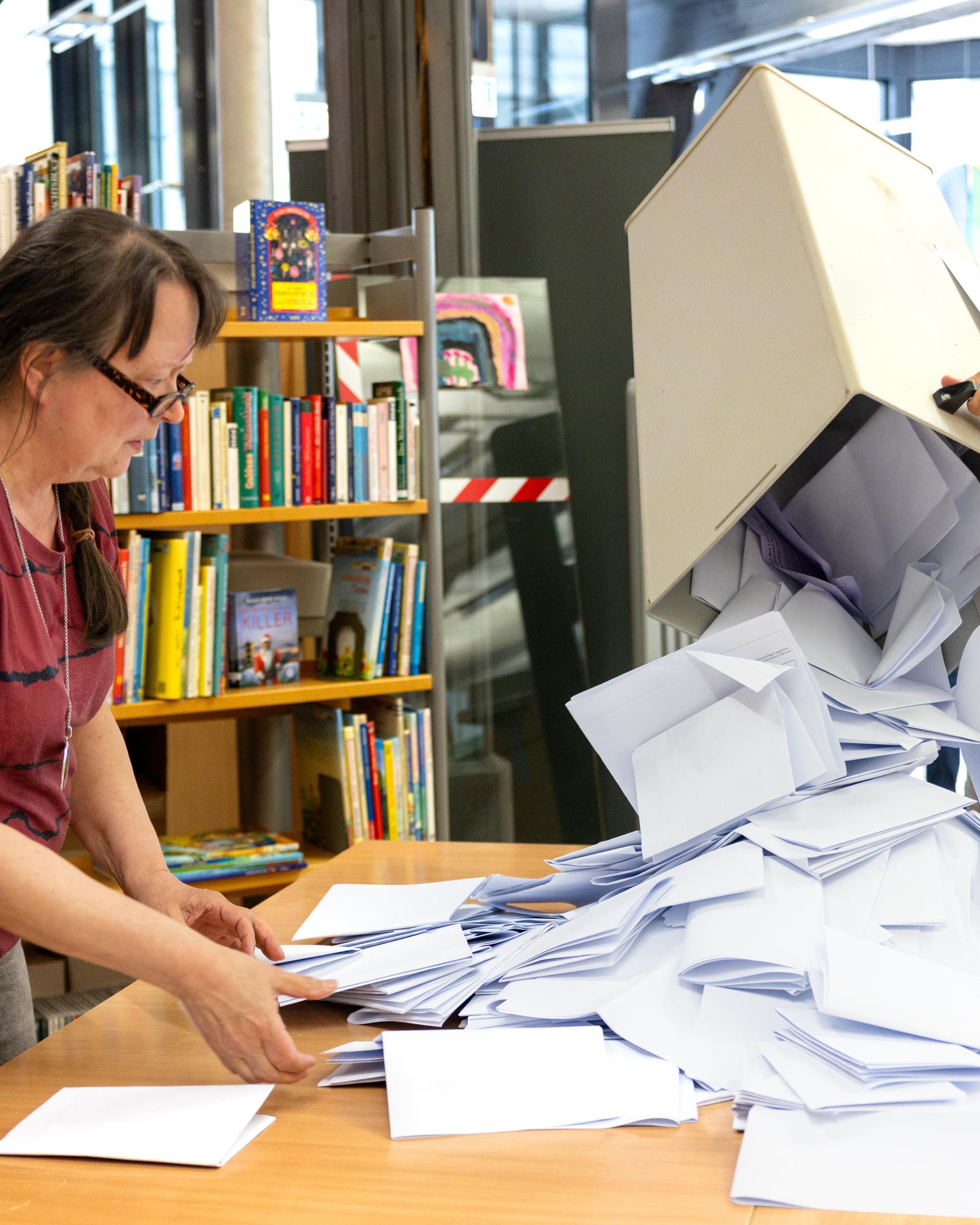  Wahlhelfer leeren in der Bibliothek im Alten Rathaus Hildburghausen die Stimmzettel für die Kommunalwahlen aus einer Wahlurne.