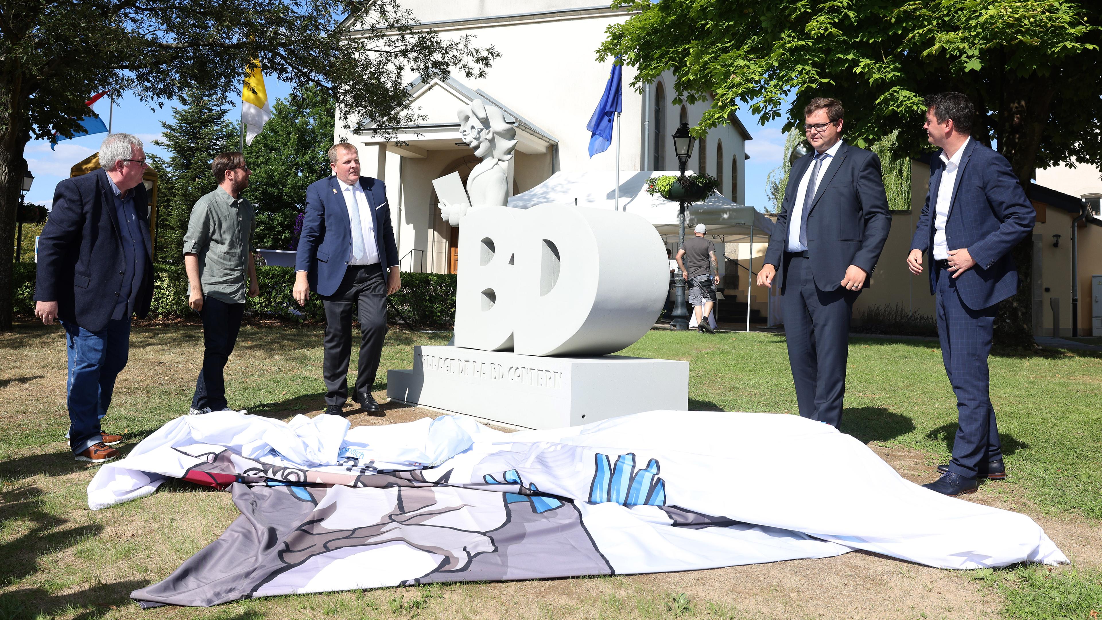 Der Minister Lex Delles, der Schöffe Tom Jungblut und Jean Claude-Muller, der Präsident von BD Contern weihen das Bédéric-Denkmal ein.