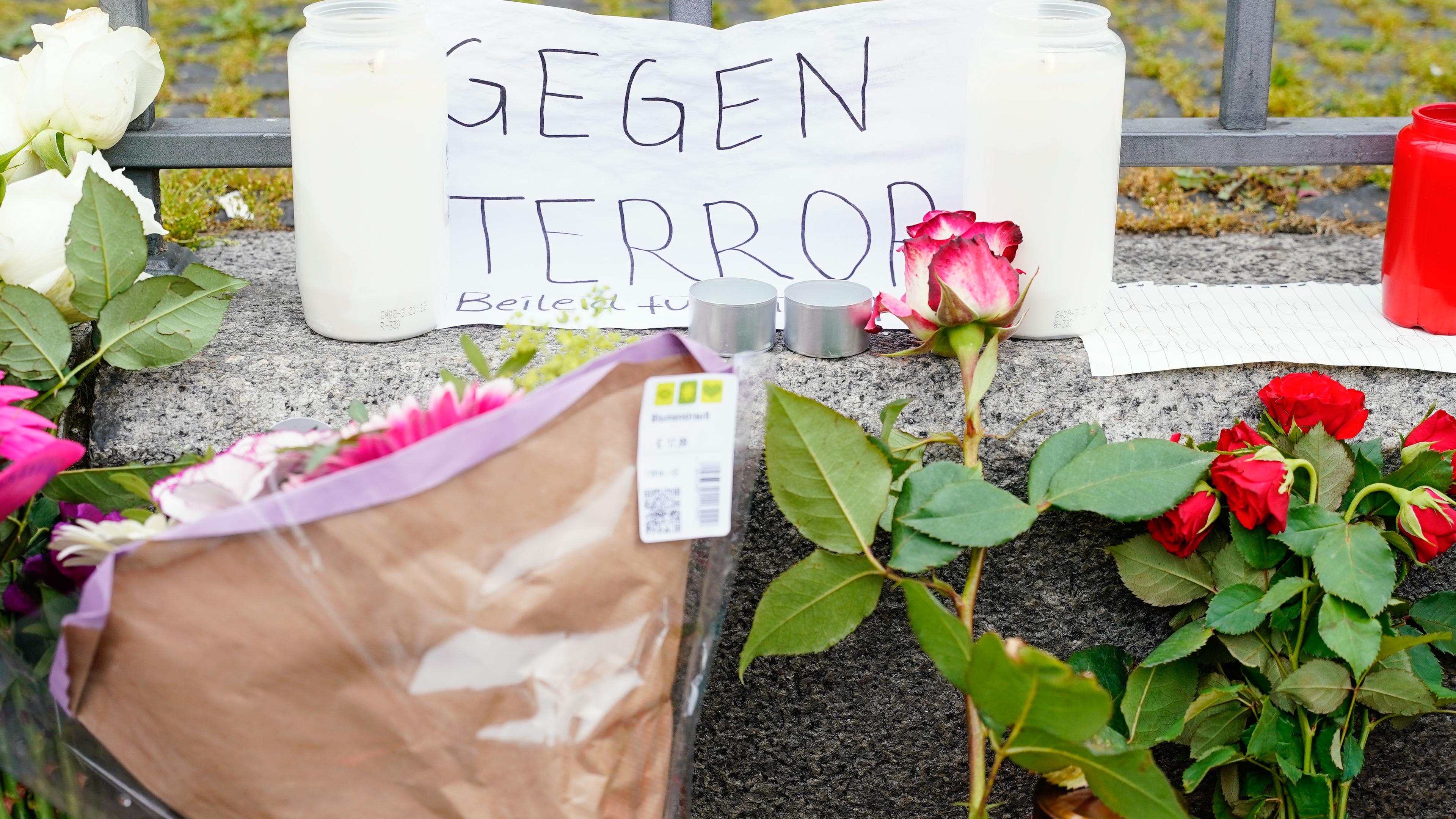 Kerzen, Blumen und ein Blatt Papier mit der Aufschrift "Gegen Terror" stehen am Tatort auf dem Marktplatz. 