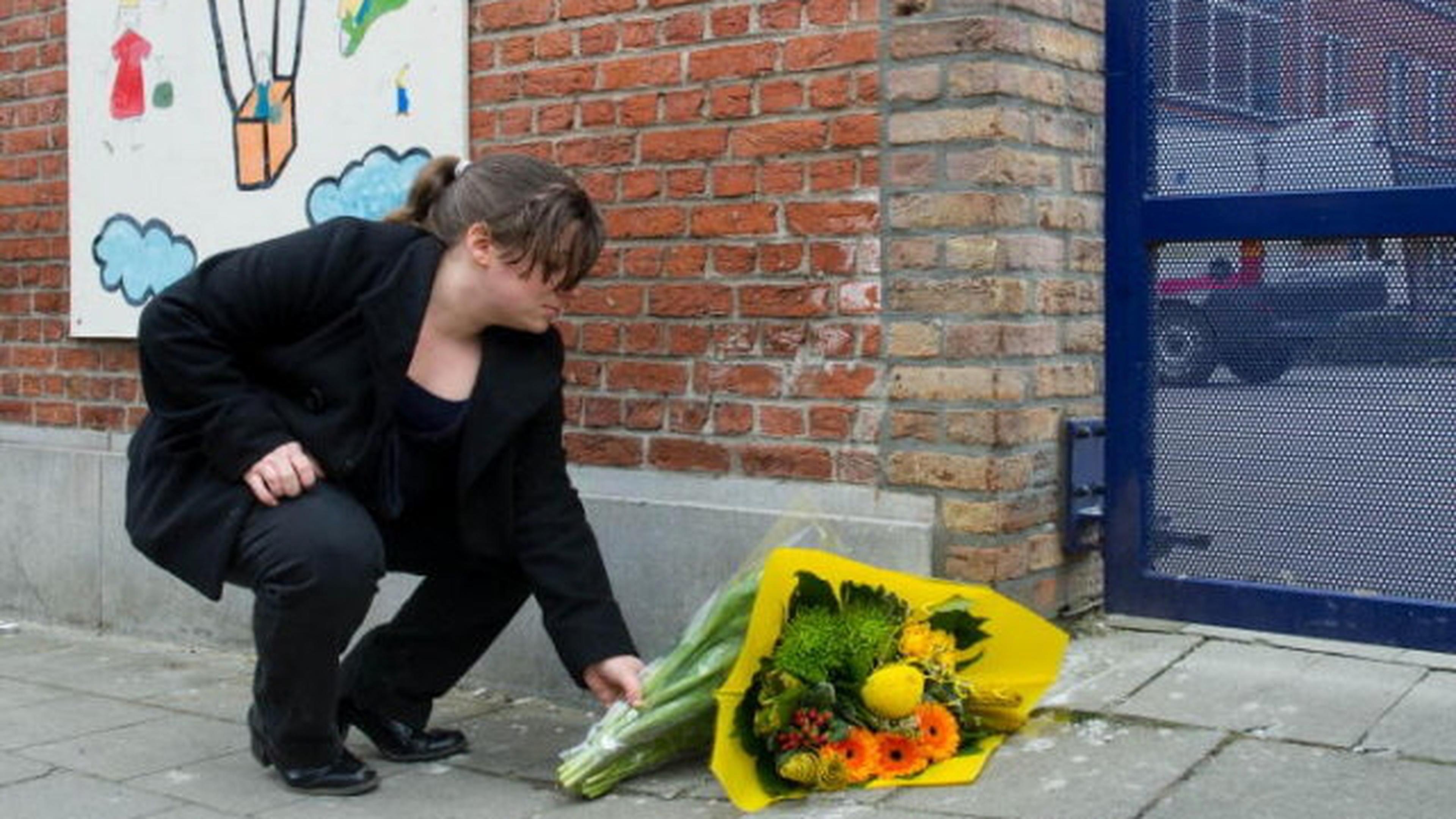 Eine Passantin legt Blumen an der Sint Lambertusschool in Heverlee nieder.
