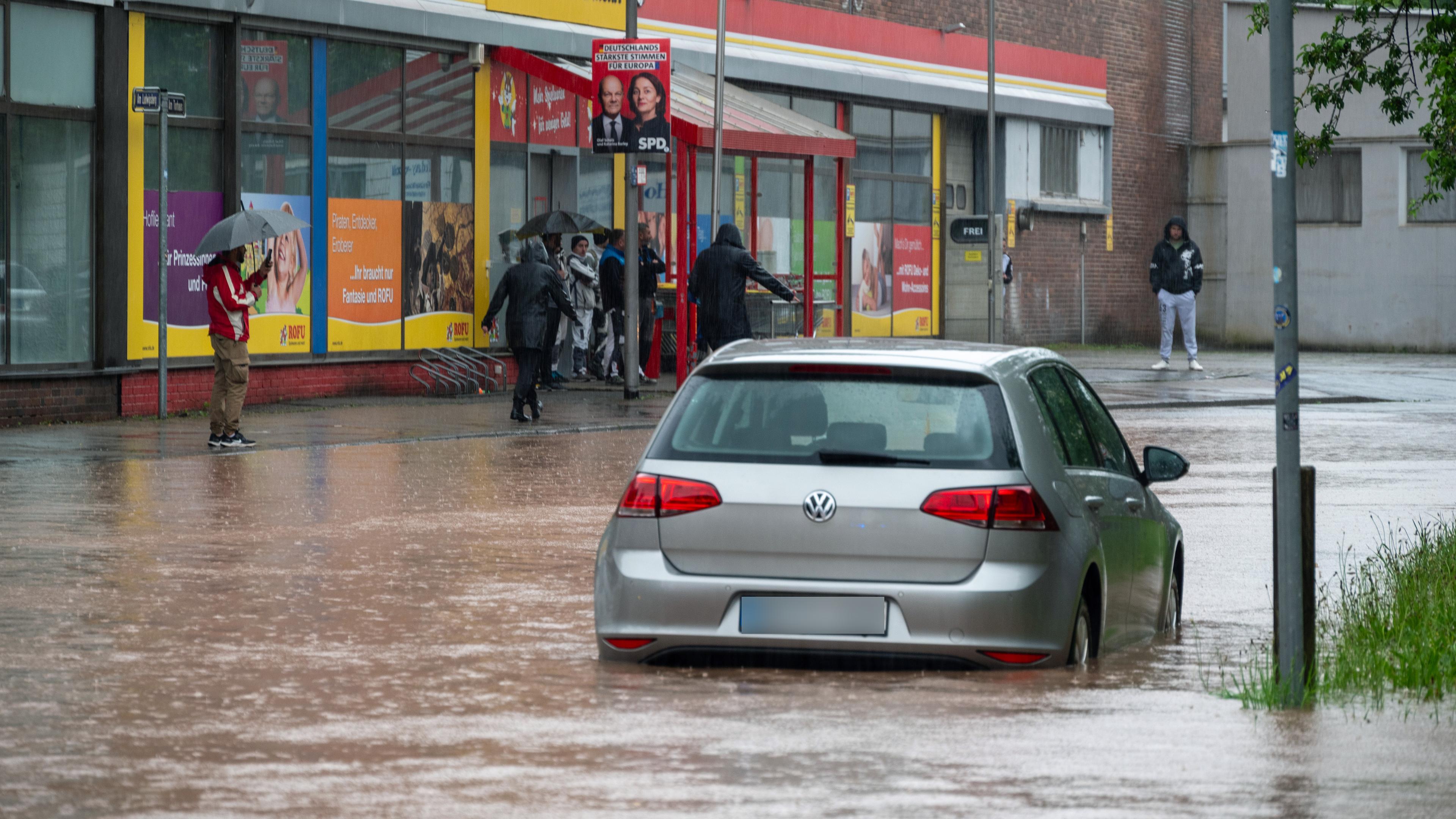 Saarbrücken am 17. Mai: Passanten stapfen und fahren durch das Hochwasser in der Fischbachstrasse in Saarbrücken. Nach starken Regenfällen steht diese teilweise unter Wasser. 
