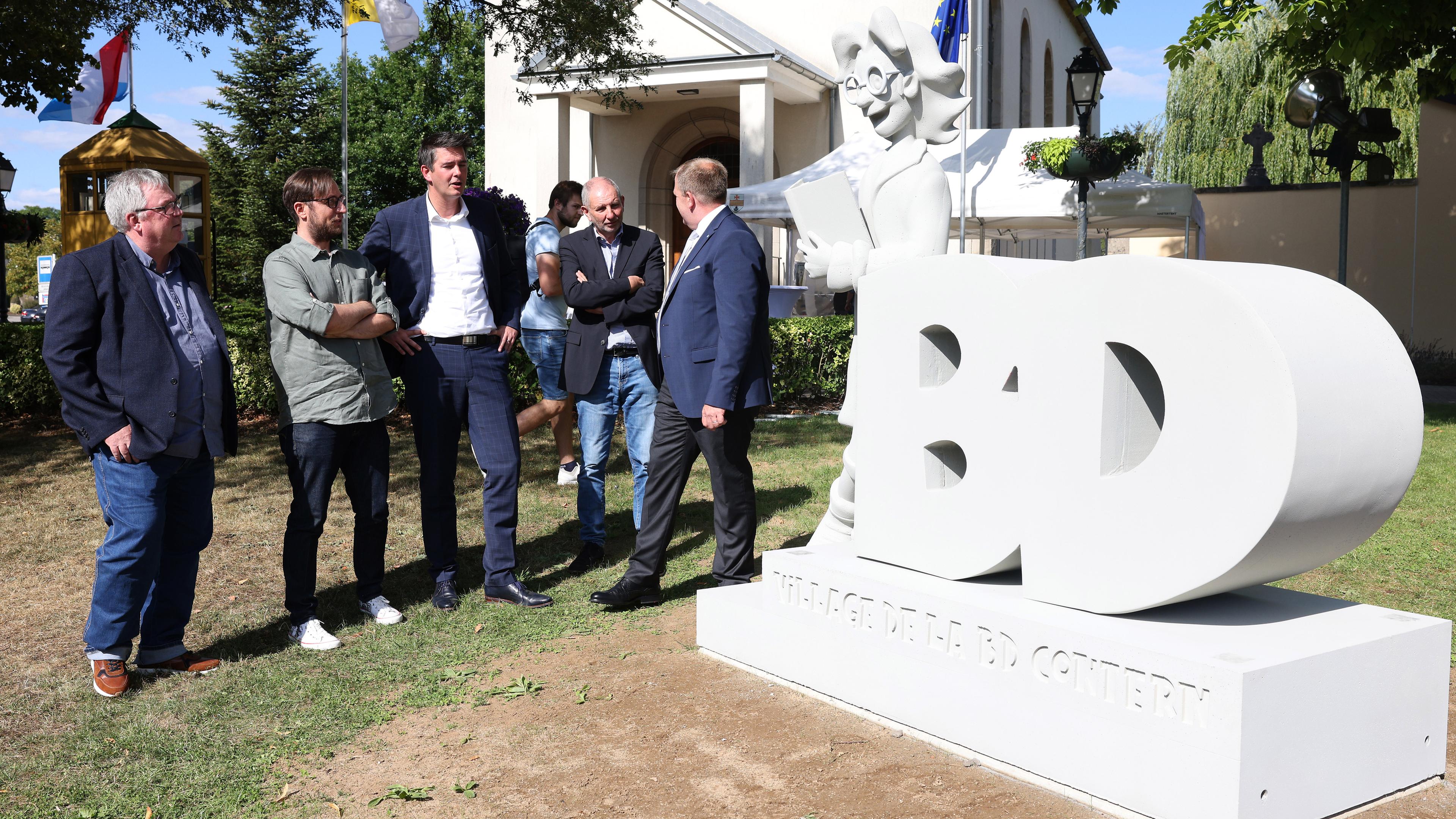 Der Minister Lex Delles, der Schöffe Tom Jungblut und Jean Claude-Muller, der Präsident von BD Contern weihen das Bédéric-Denkmal ein.