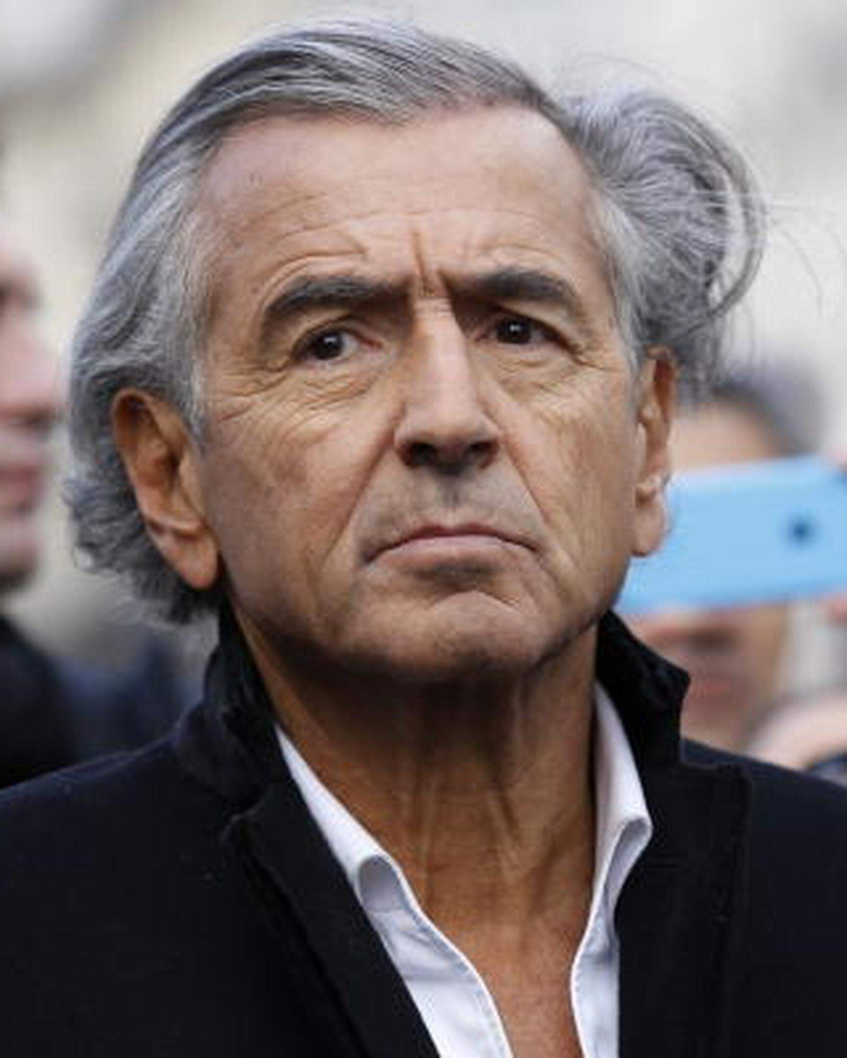 French writer Bernard Henri-Levy stands behind a banner reading "Nous sommes Charlie" (We are Charlie) before the start of a Unity rally Marche Republicaine on January 11, 2015 in Paris in tribute to the 17 victims of a three-day killing spree by homegrown Islamists. The killings began on January 7 with an assault on the Charlie Hebdo satirical magazine in Paris that saw two brothers massacre 12 people including some of the country's best-known cartoonists, the killing of a policewoman and the storming of a Jewish supermarket on the eastern fringes of the capital which killed 4 local residents.        AFP PHOTO / THOMAS SAMSON