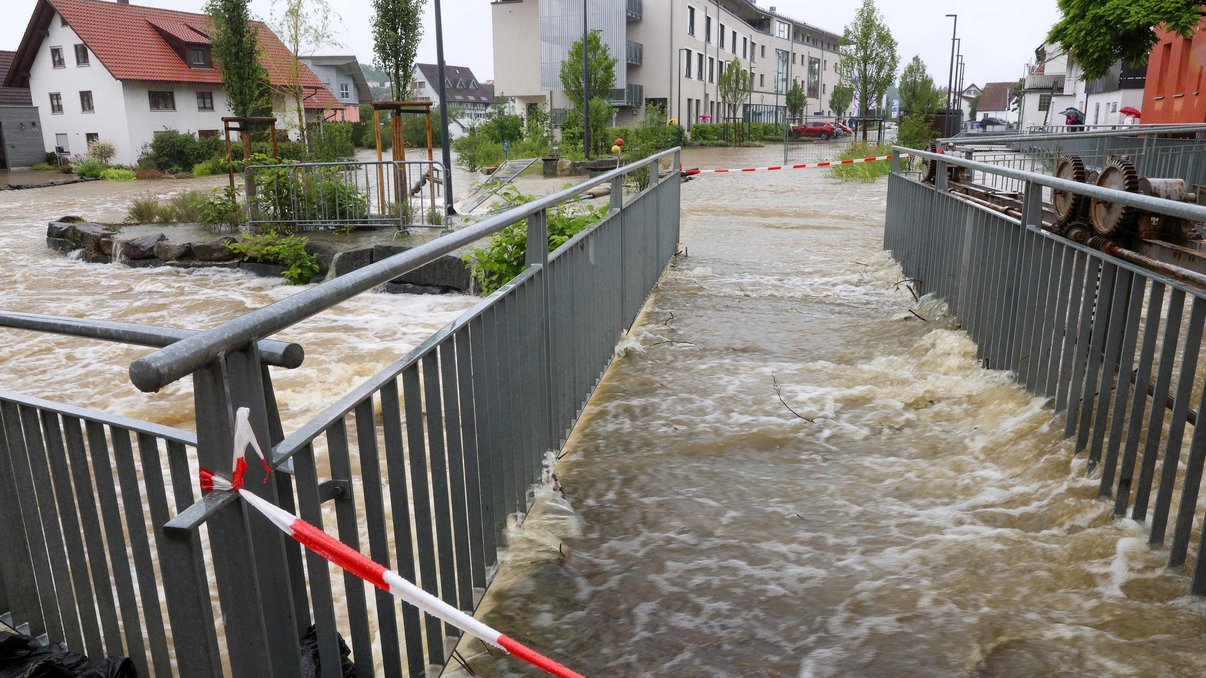 Absperrbänder sind an einer Fußgängerbrücke in der Innenstadt von Ochsenhausen angebracht. Der Fluss Rottum ist dort über die Ufer getreten.