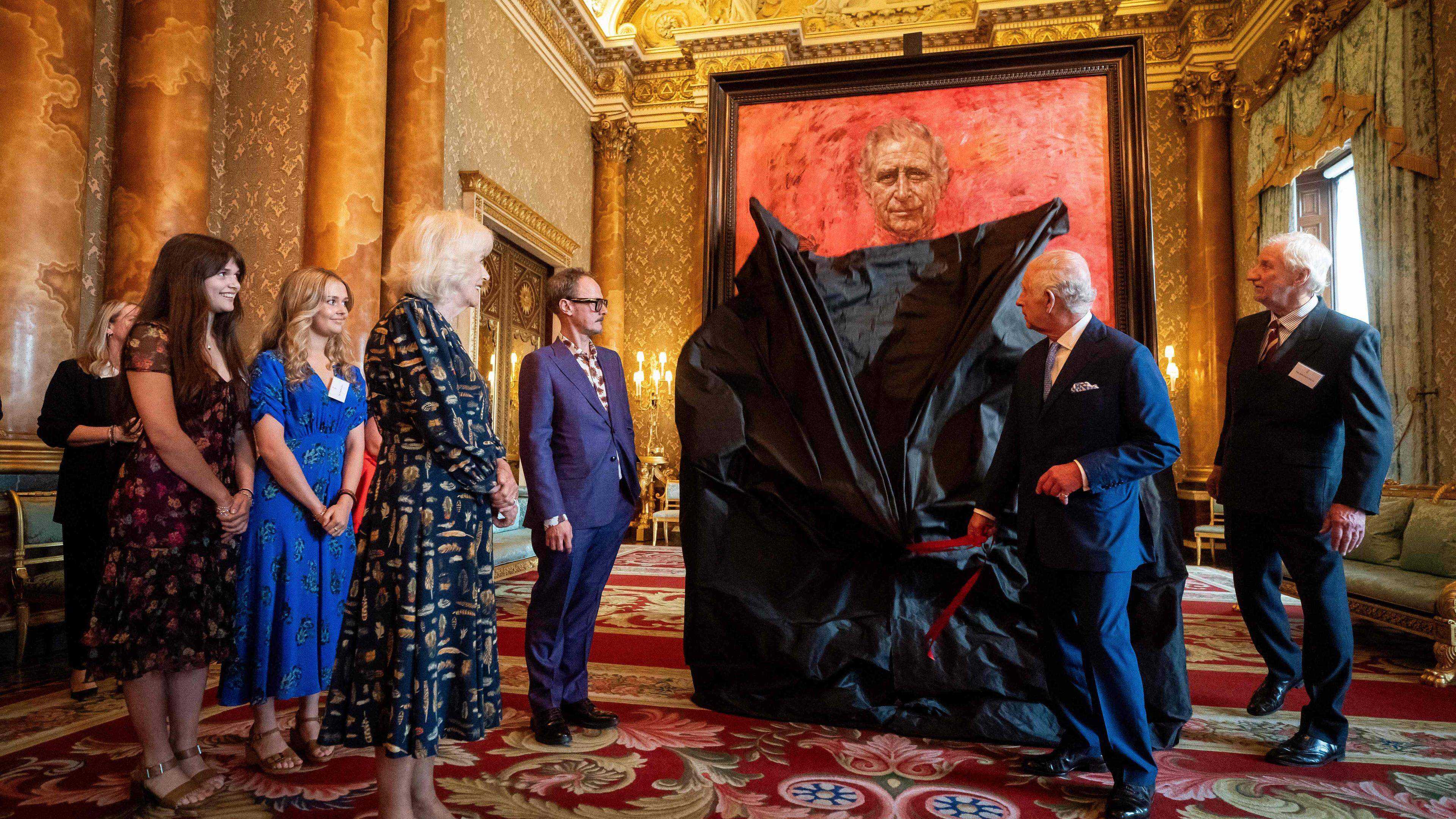 Britain's Queen Camilla (4L) watches as Britain's King Charles III (2R) unveils an official portrait of himself, by artist artist Jonathan Yeo (5L), depicting the King wearing the uniform of the Welsh Guards, of which he was made Regimental Colonel in 1975, in the Blue Drawing Room at Buckingham Palace in London on May 14, 2024. The official portrait was commissioned in 2020 to celebrate the then Prince of Wales's 50 years as a member of The Drapers' Company in 2022. Artist Jonathan Yeo had four sittings with the King Charles III, beginning when he was Prince of Wales in June 2021 at Highgrove, and later at Clarence House. The last sitting took place in November 2023 at Clarence House. Yeo also worked from drawings and photography he took, allowing him to work on the portrait in his London studio between sittings. The canvas size - approximately 8.5 by 6.5 feet when framed - was carefully considered to fit within the architecture of Drapers' Hall and the context of the paintings it will eventually hang alongside. (Photo by Aaron Chown / POOL / AFP) / RESTRICTED TO EDITORIAL USE - MANDATORY MENTION OF THE ARTIST UPON PUBLICATION - TO ILLUSTRATE THE EVENT AS SPECIFIED IN THE CAPTION