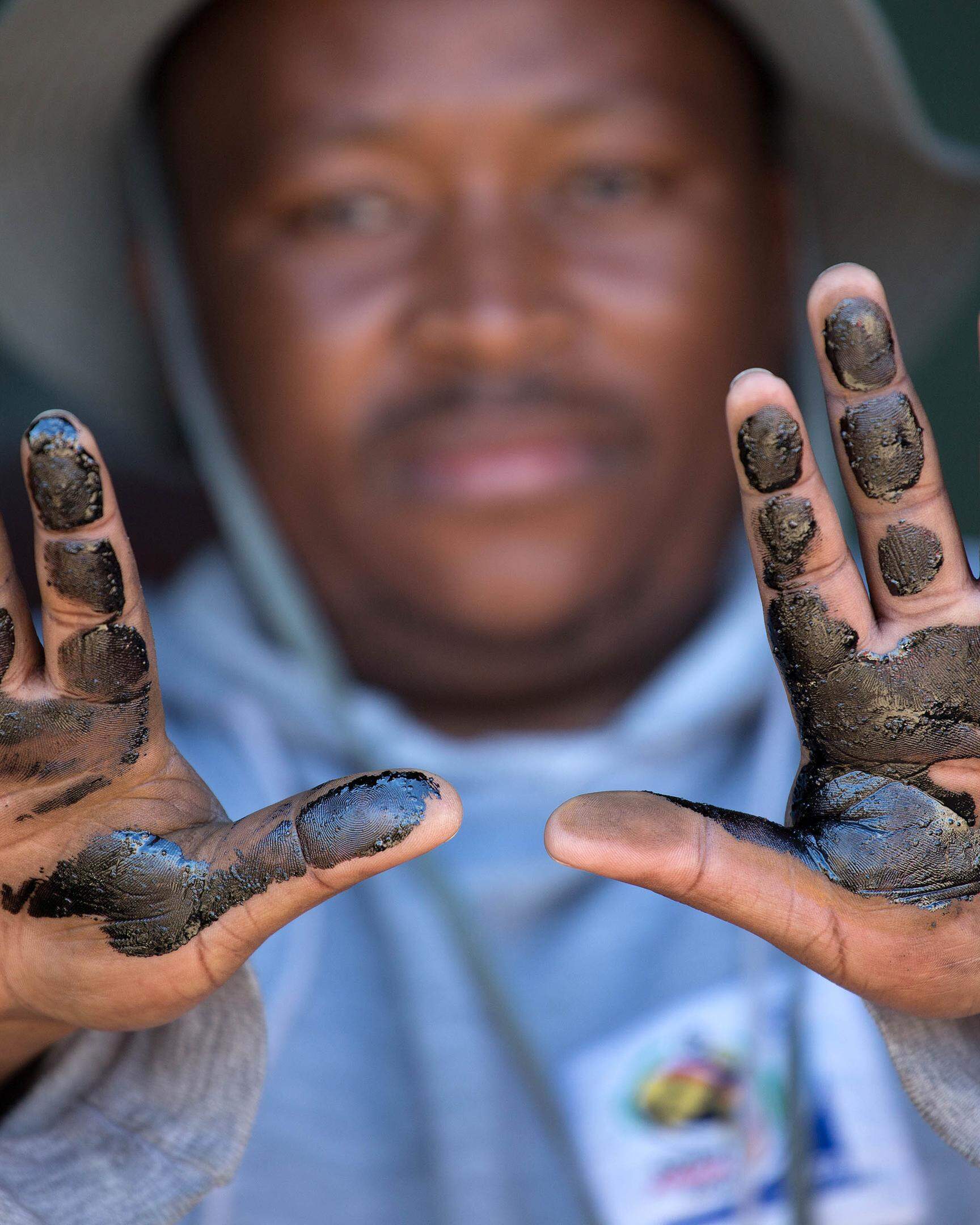 Ein Anwohner demonstriert die Auswirkungen der Umweltverschmutzungen des Werks in Südafrika. 